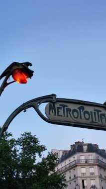 Paris 'teki Art Nouveau Metropolitain tabelası. Işıklandırılmış küre ve bina arka planda.