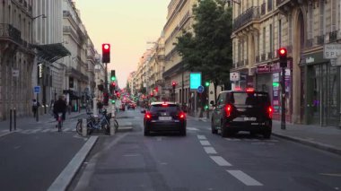 Paris, Fransa. 14 Mayıs 2025, Paris 'teki La Fayette Caddesi' nde gece trafiğinde kırmızı ışıkta bekleyen araçlar var. Binaların, ağaçların, bisikletlerin ve yayaların olduğu şehir trafiği