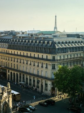 Arka planda Eyfel Kulesi olan klasik Paris sokak manzarası şehrin mimari cazibesinin özünü yansıtıyor.
