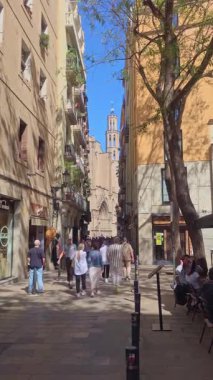 Barselona, İspanya. 24 Mayıs 2025: Güneşli bir günde İspanya 'nın Barselona şehrindeki büyüleyici El Doğan mahallesindeki yerleşim yerlerinin üzerinde yükselen Santa Maria del Mars çan kulesinin alçak açılı görüntüsü