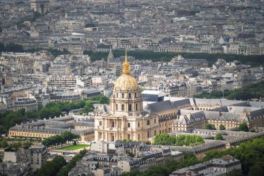 Les Invalides 'in havadan geniş açılı görüntüsü ve Paris, Fransa' nın yoğun kentsel manzarasıyla çevrili ikonik altın kubbesi. Napolyon 'un mezarına ev sahipliği yapan tarihi kompleks, geleneksel Haussmanya binaları ve yeşil alanlar arasında yer alıyor.