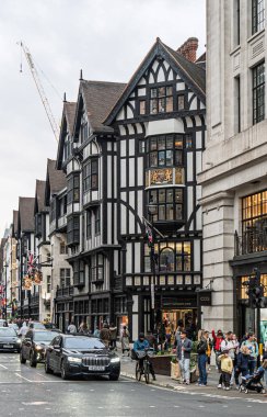Londra, İngiltere. 18 Nisan 2025, Londra 'nın önünde yürüyen ve bisikletle dolaşan turistler ve Londralılar, Great Marlborough Caddesi' nde bir Tudor diriliş tarzı bina.