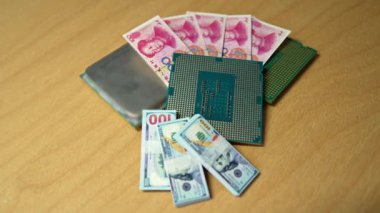 İşlemciler, Amerikan doları ve Çin Yuan banknotları tahtadan bir masanın üzerinde ABD ve Çin arasındaki teknoloji rekabetini temsil ediyor.