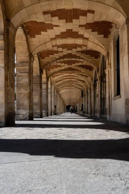 Güneşli bir günde Paris, Fransa 'da Vosges Meydanı' nın kemerlerinin altında uzanan uzun gölgeler.