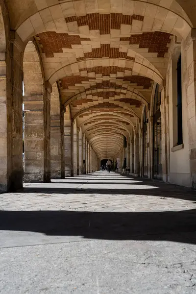 Güneşli bir günde Paris, Fransa 'da Vosges Meydanı' nın kemerlerinin altında uzanan uzun gölgeler.