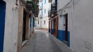 Peniscola, Castellon dar sokağında beyaz ve mavi evlerle güneş parlıyor.