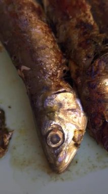 Beyaz bir tabakta iki ızgara sardalya, geleneksel bir Akdeniz yemeği.