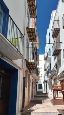 Peniscola, Castellon dar sokağında beyaz ve mavi evlerle güneş parlıyor.