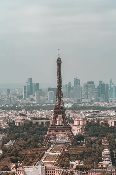 Eyfel Kulesi, Paris 'in şehir manzarasının ortasında, bulutlu bir gökyüzüne karşı kentsel güzelliği ve ikonik simgeyi gözler önüne seriyor.