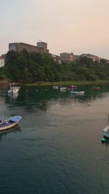 San Vicente de la Barquera kalesinin huzurlu günbatımı manzarası Cantabria, İspanya 'daki denizi yansıtıyor.