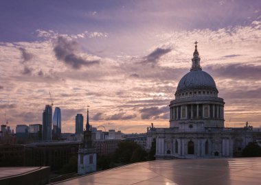 St Pauls Cathedral dome and cross standing prominent in the London skyline. Reflecting the glow of a dramatic sunset with modern buildings and construction cranes shaping the evolving urban landscape