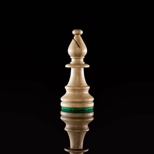 Wooden white chess bishop isolated at dark background with transparent reflection on the floor