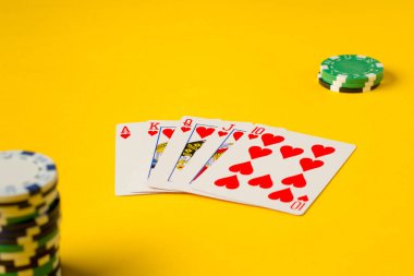 Floş Royal. Beş iskambil kâğıdı - poker kraliyet floş eli. Poker fişleri sarıya. Kumarda başarı