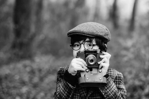 公園でぼやけた背景にレトロなカメラを持つ少年 公園を背景にレトロなカメラを持った少年 白黒写真 — ストック写真