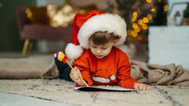 Noel Baba şapkalı küçük çocuk Noel Baba 'ya mektup yazıyor.