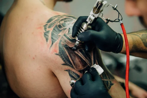 stock image the process of creating a tattoo on the back of a man. Professional tattoo.