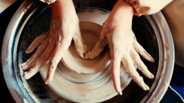 Bir çömlekçinin eli çömlekçinin çarkına bir sürahi kil yontuyor.