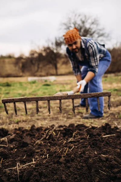 Rolnik Pracujący Ogrodzie Pomocą Zgrabiarki Wyrównującej Zaorany Grunt Słoneczny Dzień — Zdjęcie stockowe
