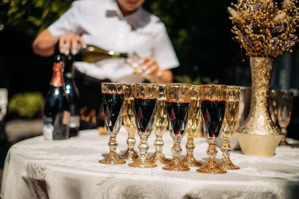 Waiter pouring champagne into glass. Buffet table on the street