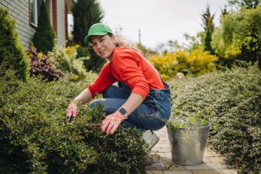 Genç bir kadın baharda büyük bahçesinde yabani otları çekiyor, kıştan sonra bahçeyi temizliyor.