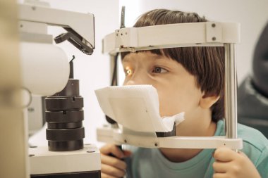 Optimetri kavramı. Optometrist, göz hekimliği kliniğinde bir çocuğun görüşünü kontrol eder..
