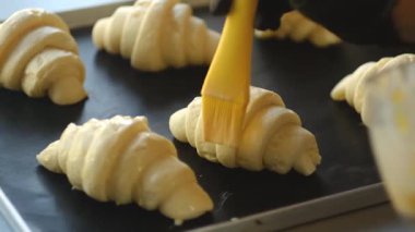 Taze oluşmuş kruvasanlar yumurta sarısı ile fırçalanır ve pişirilmeye hazırdır. Bu ev yapımı hamur işleri, geleneksel Fransız usulü yumuşak, tereyağlı hamur işleriyle ayırt edilir..