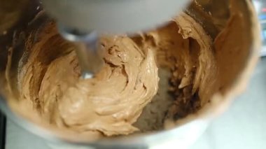 Bir stand mikser paslanmaz çelik bir kasede pürüzsüz bir hamur yoğurur ve profesyonel bir mutfakta süreci gözler önüne serer. Kremalı karışım, taze malzemeler kullanarak pişirme sanatının bir örneği..