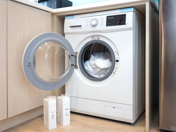 White front load washing machine at small kitchen.  A washing machine integrated in the kitchen furniture