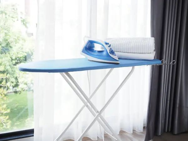 Electric steam iron and pile of clothes on ironing board