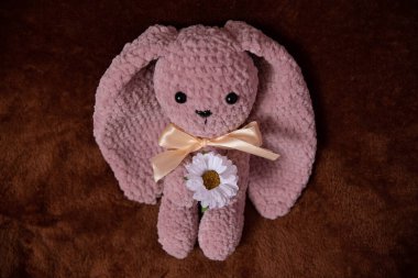 beautiful knitted pink bunny, with a lily flower near the box on a fluffy background
