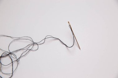 Beyaz arkaplanda ipliği olan iğne
