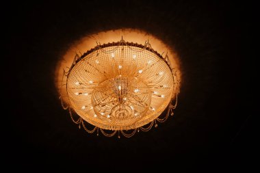 Tiyatronun tavanında nefis, büyük, altın bir avize. Tiyatronun tavanında büyük, zarif bir avize.