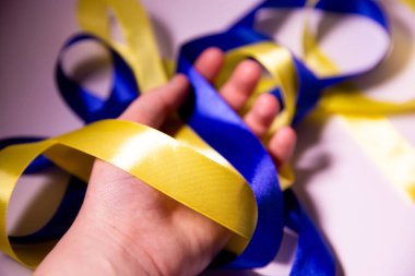 Elinde sarı-mavi kurdele, elinde saten kurdele, elinde Ukrayna bayrağı renginde kurdele.