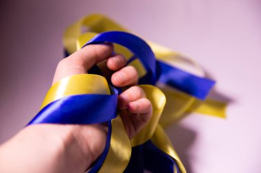 Elinde sarı-mavi kurdele, elinde saten kurdele, elinde Ukrayna bayrağı renginde kurdele.