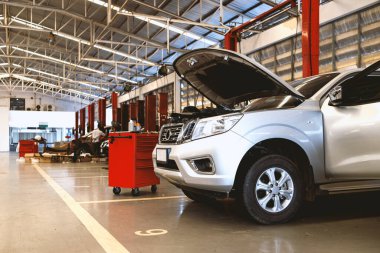 Garaj servis istasyonunda araba tamiri. Arka planda hafif odaklı ve ışığın üstünde.