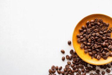 Saf beyaz arka planda sıcak kahve ve fasulye kaynayan bir fincanın yakın çekimi. Koyu kahve çekirdeklerinin aromatik karışımı güne başlamak için nefis bir uyanış vadediyor.