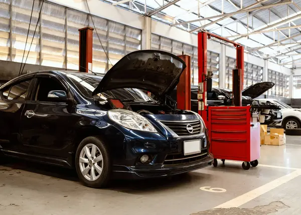 Otomotiv bakım ortamını gözler önüne seren, asansörlerde ve aletlerde birden fazla araba bulunan yoğun bir araba tamir atölyesi.