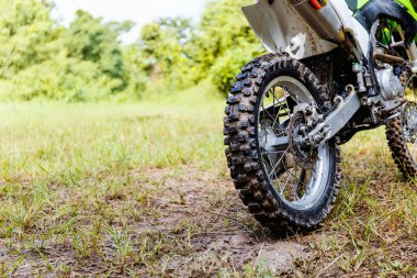 Bir arazi motosikletçisinin engebeli bir pistte yol alırken, off-road motosiklet ve macera sporlarının heyecanını ve yoğunluğunu yakaladığı yakın plan.