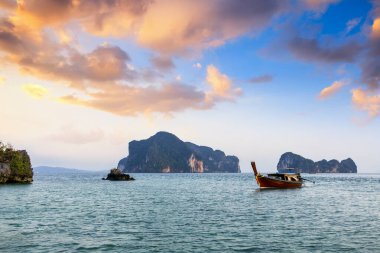 Tayland, Krabi 'deki Koh Phakbia adasında dinlenen güzel uzun kuyruklu tekne berrak mavi suları, kireçtaşı kayalıkları ve sakin bir tropikal atmosferi var..