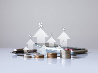 Artan faiz oranları, finansal büyüme ve yatırım fırsatlarını sembolize eden, yüzdelik büyüme okları ve hesap makinesi içeren birikmiş paralar.  