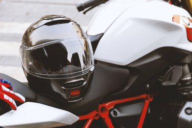 Bigbike koltuğunda dinlenen siyah bir motosiklet kaskının yakın çekimi güvenliği, korumayı ve binicilik takımlarını sembolize ediyor..