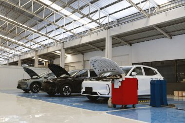 Profesyonel bir oto tamirhanesinde, bakım ve teftiş için hidrolik asansörün altına yerleştirilmiş elektrikli bir araç..