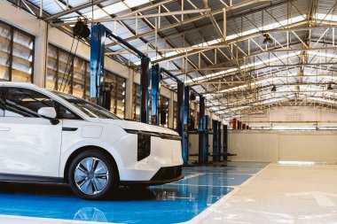 Profesyonel bir oto tamirhanesinde, bakım ve teftiş için hidrolik asansörün altına yerleştirilmiş elektrikli bir araç..