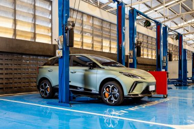 Profesyonel bir oto tamirhanesinde, bakım ve teftiş için hidrolik asansörün altına yerleştirilmiş elektrikli bir araç..