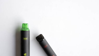 Beyaz arka plana yerleştirilmiş siyah bir yelek cihazının minimalist görüntüsü. Vaping, e-sigara ve modern yaşam tarzı ile ilgili konular için ideal..