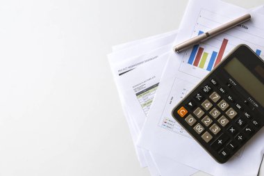 Hesaplayıcı, mali belgeler, iş raporları ve planlama ve muhasebe için beyaz bir masanın üzerine bir kalem içeren mali analiz kavramı.
