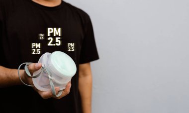 PM2.5 ve PM10 hava kirliliğinden korumak için N95 maskesi tutan bir adamın yakın çekimi, sağlık güvenliği ve solunum korumasını vurguladı.