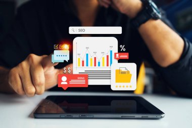 SEO ölçümlerini, finansal grafiklerini analiz etmek ve iş hedeflerine ulaşmak için hesap makinesi ve veri görselleştirme araçları kullanan bir işadamı.
