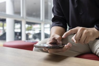 Modern kapalı alanda akıllı telefon kullanan bir adamın yakın çekimi. İş gündelik tarzı, rahatlatıcı, teknolojik yaşam tarzı, iletişim konsepti.