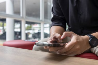 Modern kapalı alanda akıllı telefon kullanan bir adamın yakın çekimi. İş gündelik tarzı, rahatlatıcı, teknolojik yaşam tarzı, iletişim konsepti.